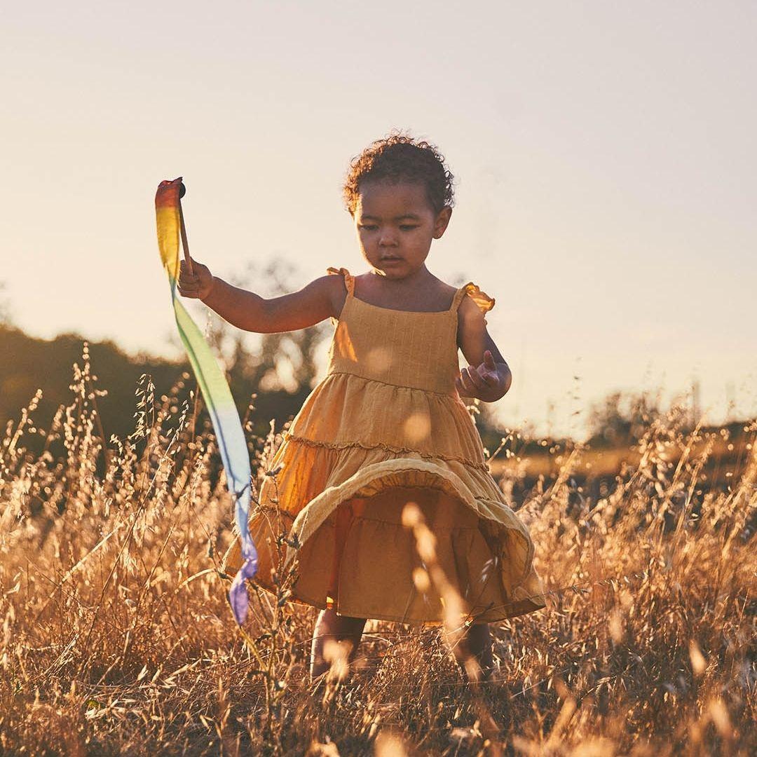 Little girl playing on the meadow with a Sarah's Silk silk streamer.