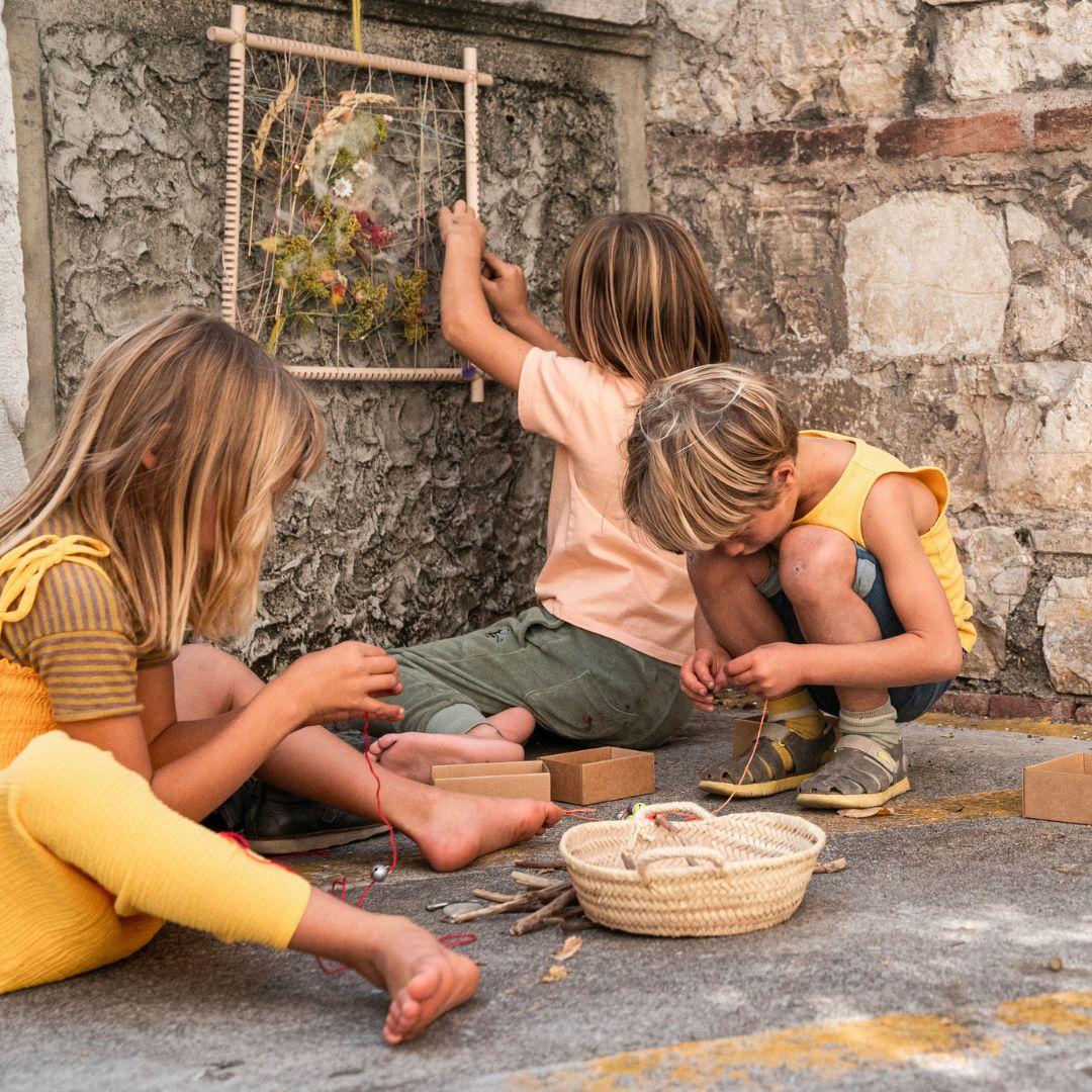 A picture from Grapat's new Happy Place campaign featuring children sitting on the street playing, and making a creative picture using the new wooden frame.